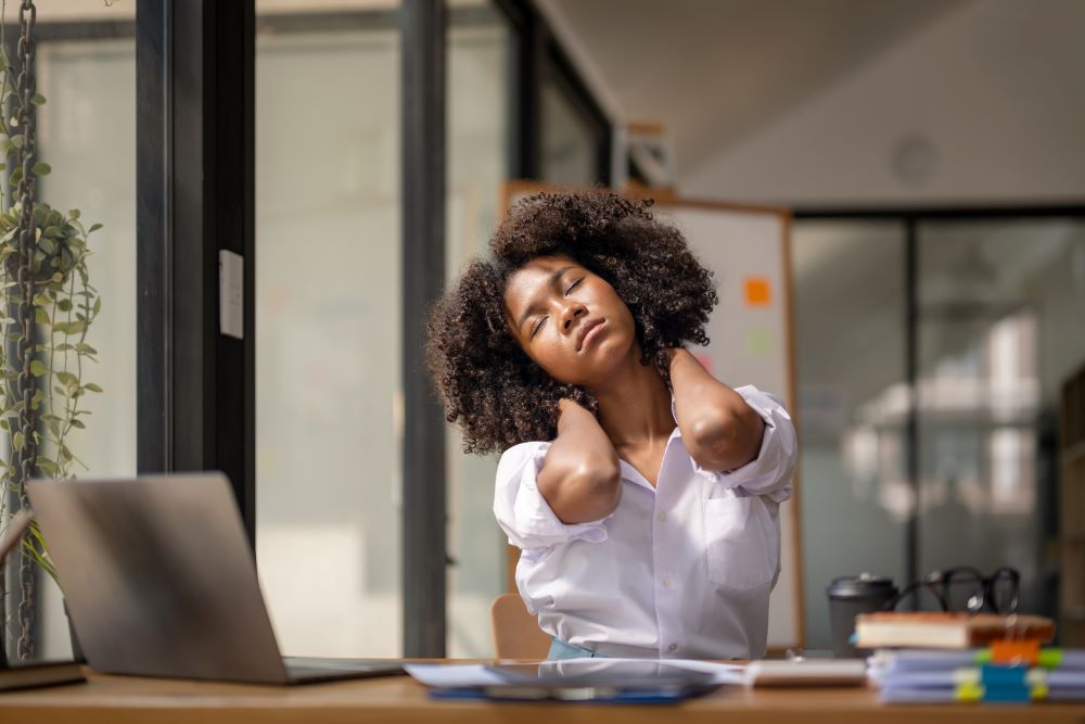 Black woman stretching sitting at her desk