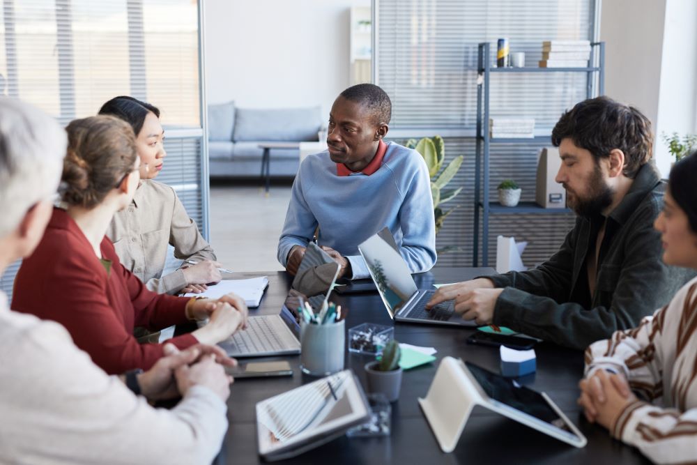 Portrait of diverse group of business people at table collaborating during briefing meeting in office