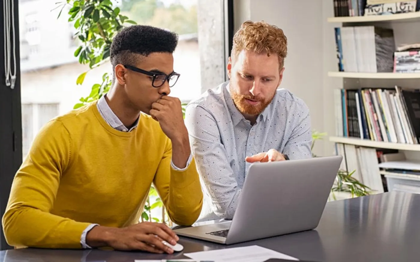 Two people in an office working together at a laptop.